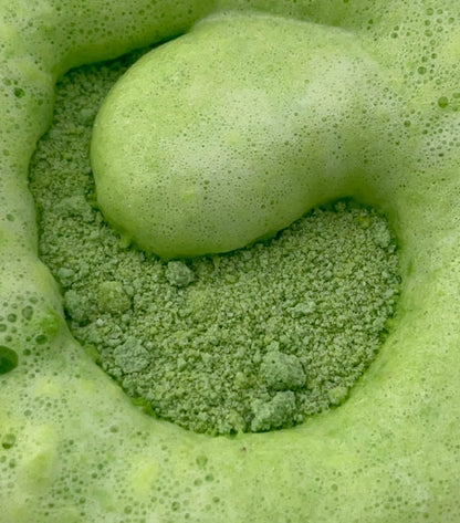 Close-up of green potion powder beginning to fizz in water with bubbles