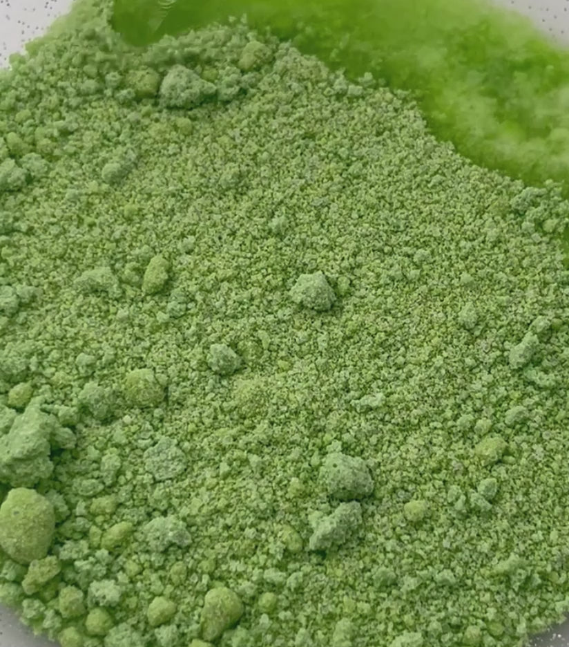 A video of green potion powder - water is dropped on and it fizzes and bubbles